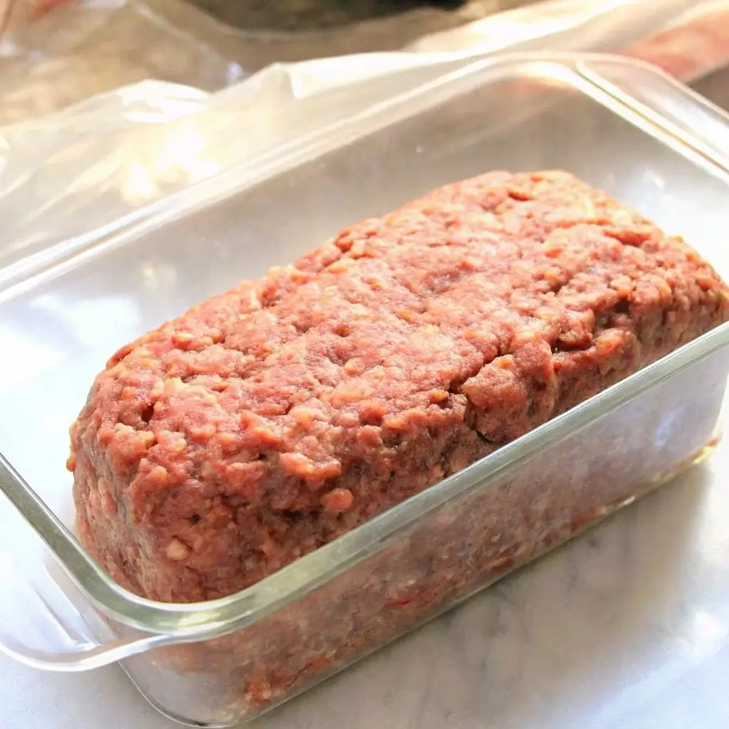 Hackbraten in einer Glasform geformt und bereit zum Backen – saftige Masse aus Hackfleisch, Zwiebeln und Eiern, perfekt vorbereitet für den Ofen.