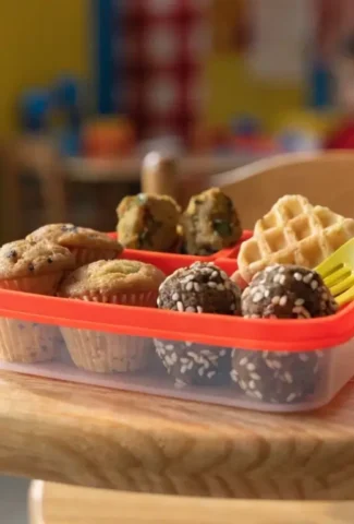 Ideen für die Kindergarten Brotdose: Diese bunten Snacks machen kleinen Kindern Freude und liefern Energie für den Tag! gesunden Snacks: Muffins, Waffeln und Energiebällchen auf Holztisch im Kindergarten